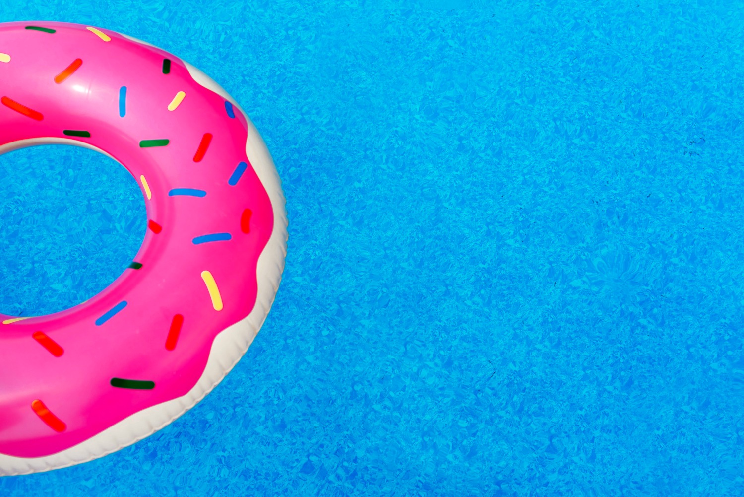 Rubber ring decorated like a doughnut in the blue water of a swimming pool - - why it's important for children to learn to swim
