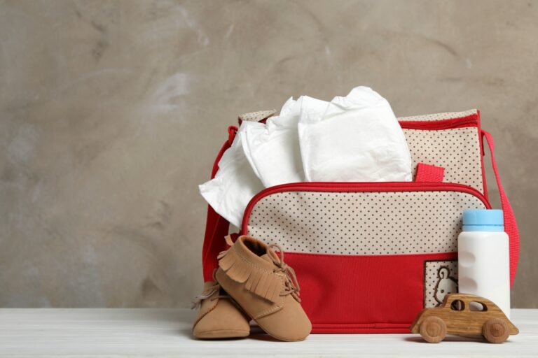 Baby changing bag with nappies sticking out plus bottle and toy car - searching for the perfect baby change bag for travel