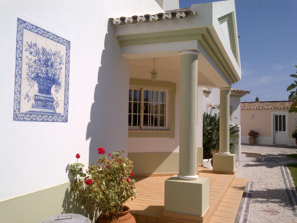 Entrance to white villa in the Algarve with blue tiles and flowers