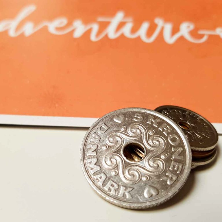 A pile of Danish krone with a sign for adventure in the background - my review of Copenhagen's city pass. Is the Copenhagen Card worth the money?