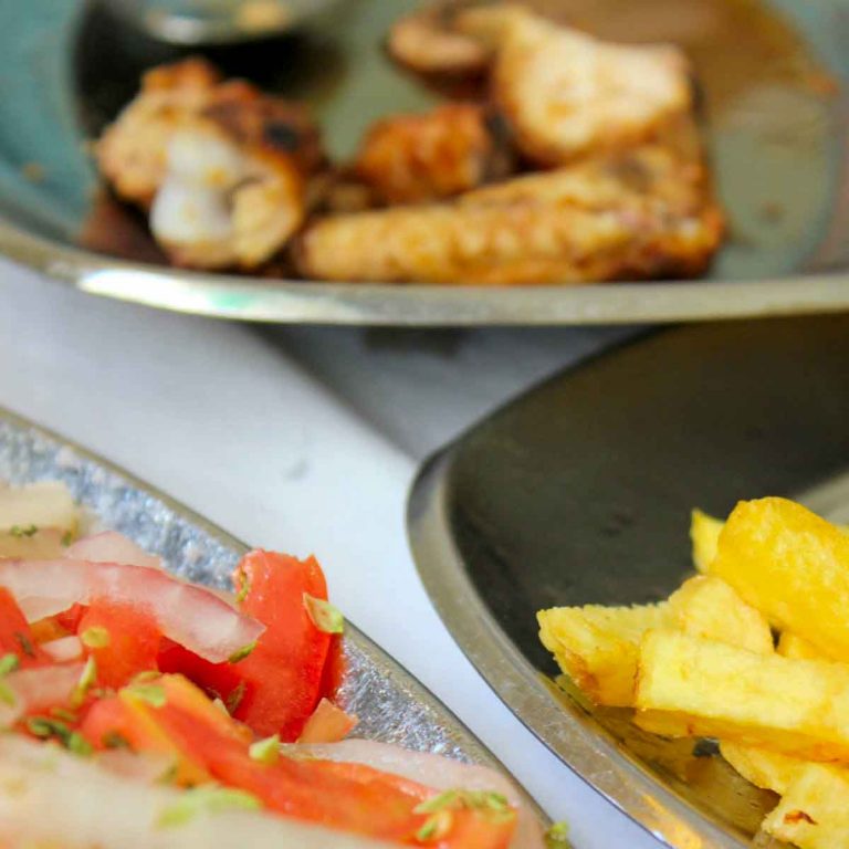 A view of the dishes on offer at Ramires restaurant - tomato salad, chips and piri piri chicken. Where was piri piri chicken invented? Here in Guia on Portugal's Algarve
