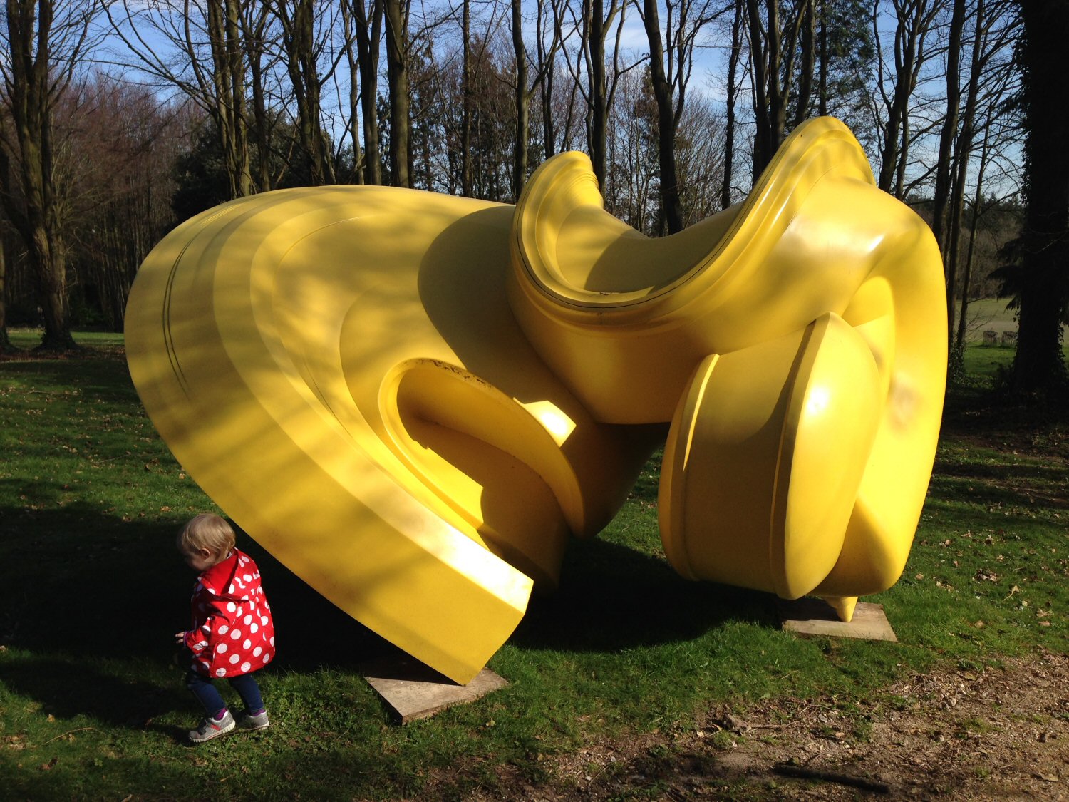 My toddler daughter by a huge yellow sculpture outdoors - discovering the Cass Sculpture Foundation with kids