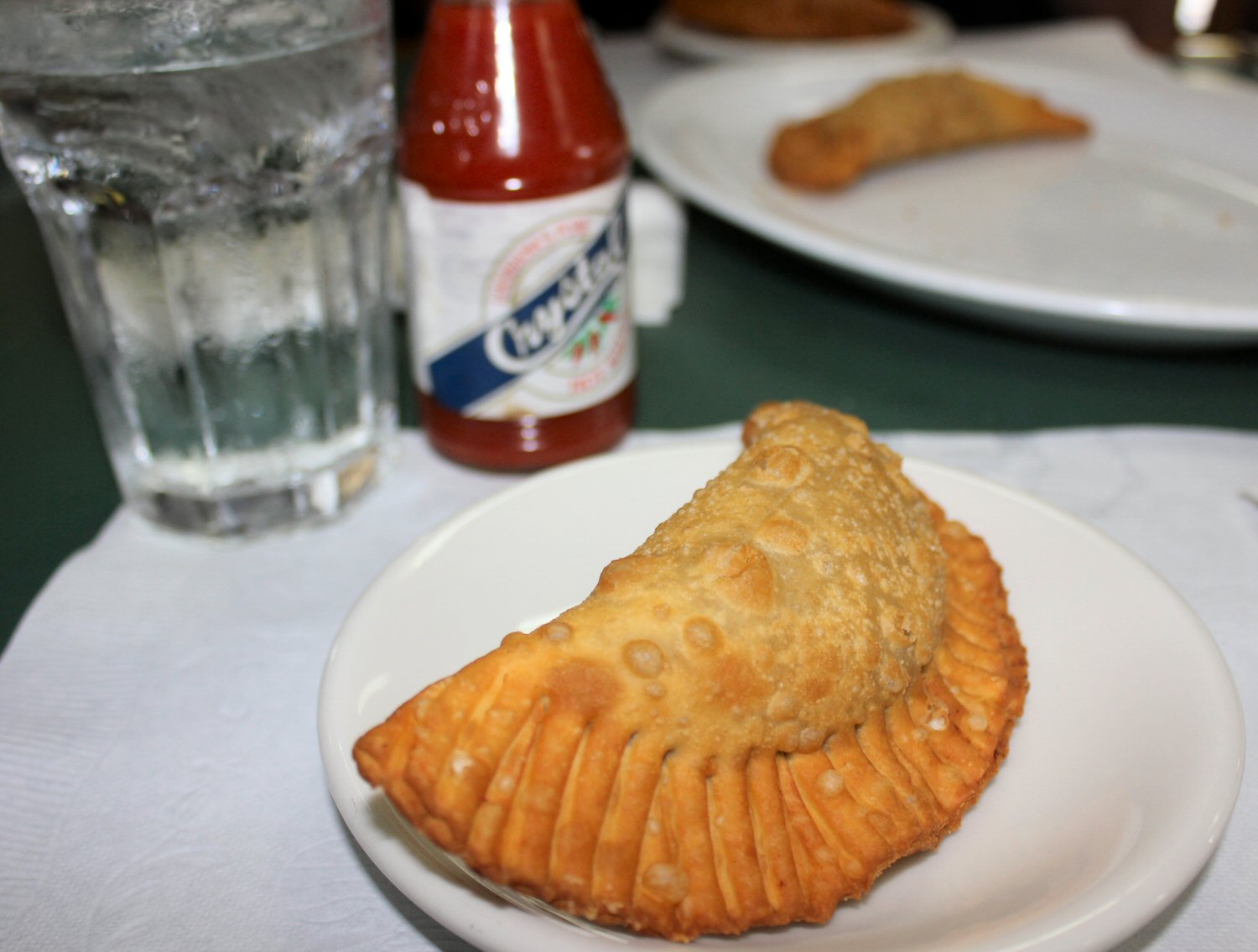 Empanada on a plate with bottle of sauce visible during a Miami food tour with kids