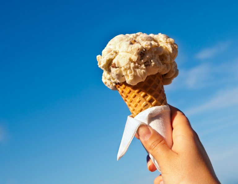 Hand holding an ice cream cone against a blue sky - discovering some of Granada's top ice cream before my trip