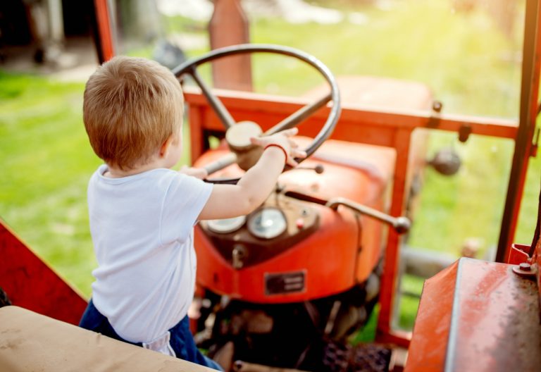 Baby boy holds the wheel of a tractor - the best family-friendly luxury farm stays