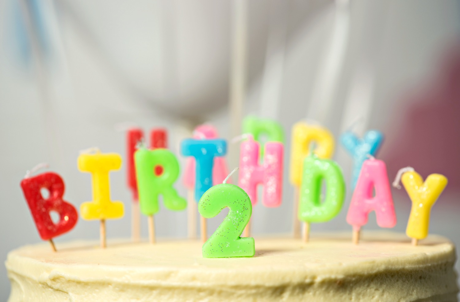 Brightly coloured cake decorations reading Happy birthday on a cake with the number two - looking back on two years of travel with a child