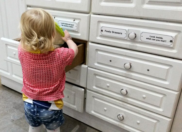 My daughter opening drawers in the play kitchen at the National Children's Museum - why a day at Eureka for toddlers is perfect
