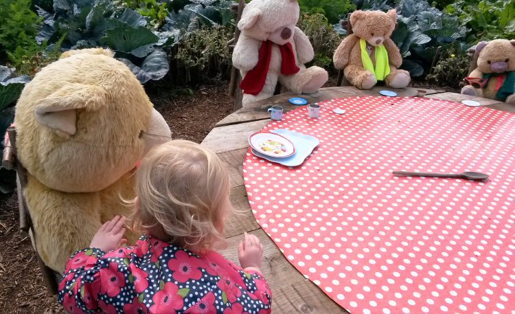 My toddler daughter rearranges the table at the teddy bear's picnic at Packwood House National Trust property in Warwickshire
