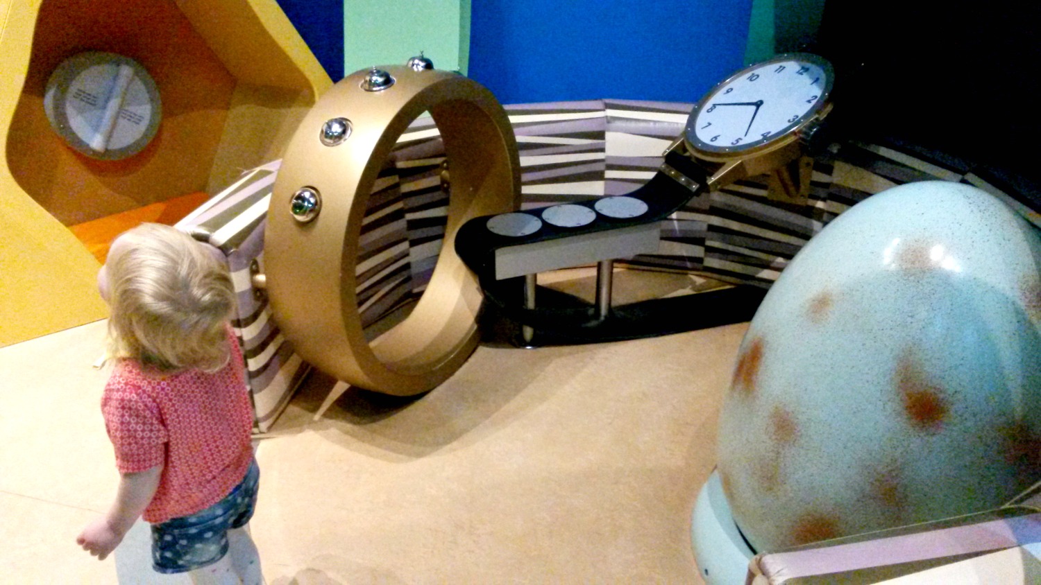 My toddler daughter learning about sound in Eureka National Children's museum, surrounded by exhibits