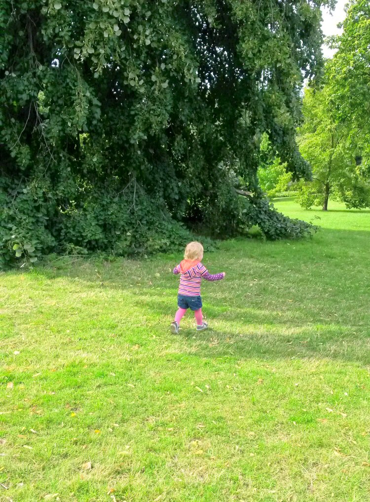 My toddler daughter runs across the grass at Kew Gardens