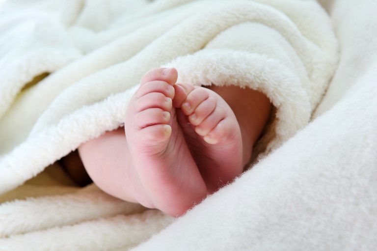 Newborn feet poking out of a blanket - remembering travel with a newborn