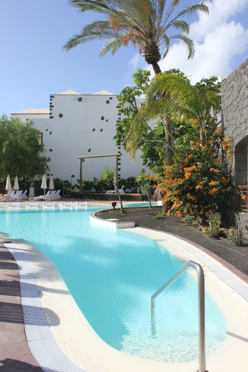 Pool at the Gran Castillo hotel Lanzarote with white buildings and palm tree in the background
