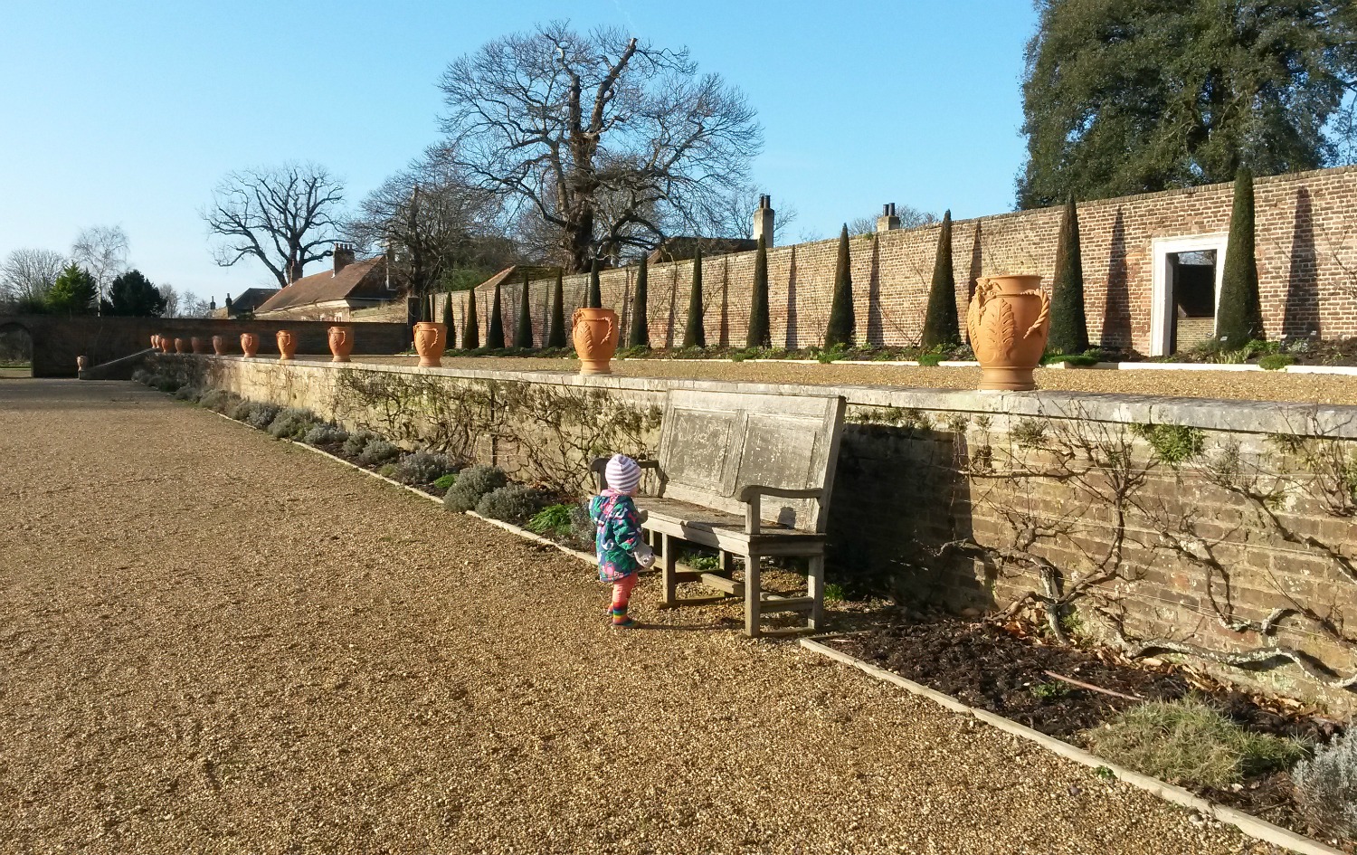 My toddler investigating the bench by decorative pots on the terrace at Ham House in Surrey