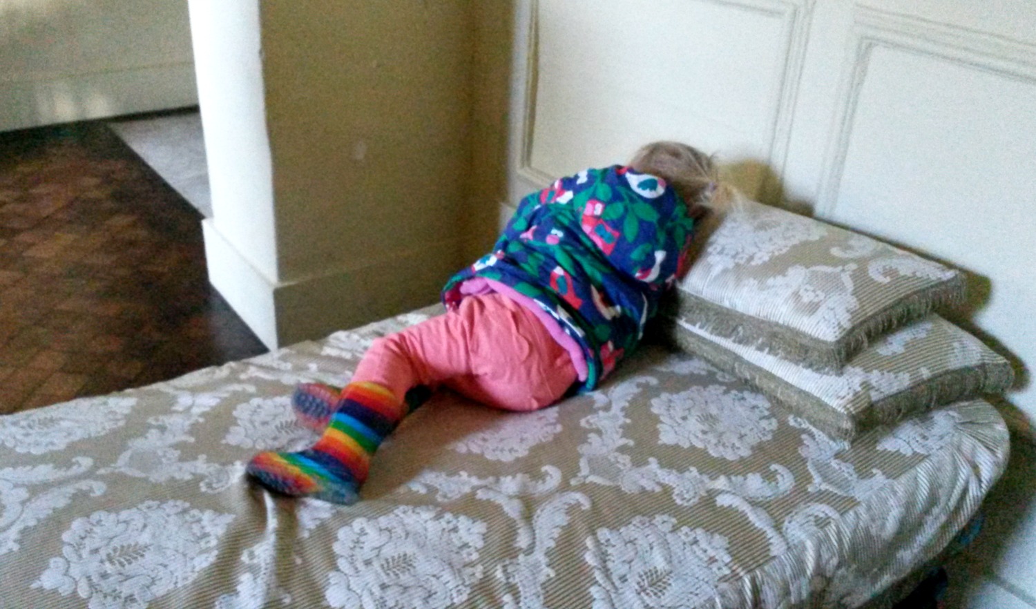 My toddler pretending to nap on the day bed in the bathroom at Ham House in Surrey