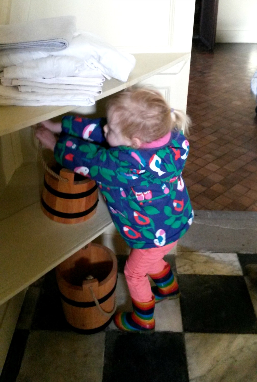 My toddler reaching for an old-fashioned wooden bucket in the bathroom at Ham House in Surrey
