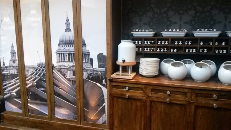 Crockery piled up on the wooden sideboard next to a wall decorated with a photo of St Paul's and the London skyline at the Mercure London Bridge hotel - my review