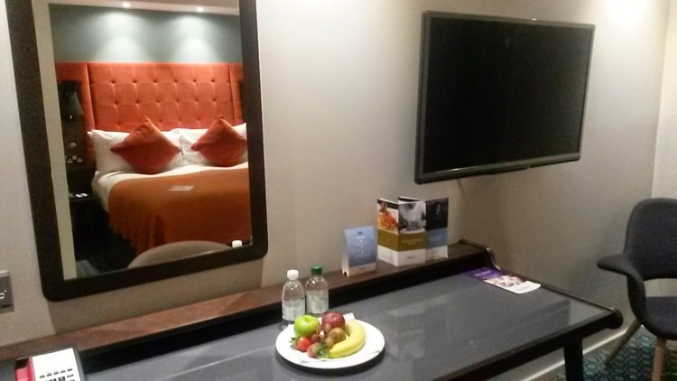 Double bed reflected in the mirror, plus plate of fruit and water on the tables of my room at the Mercure London Bridge hotel - my review