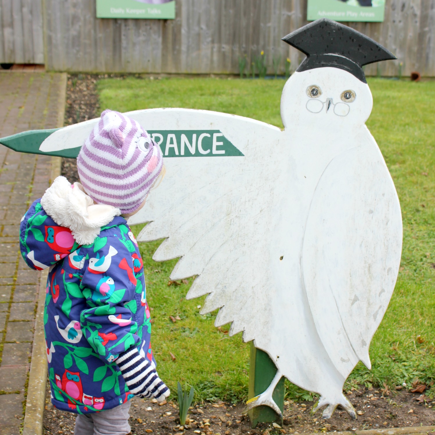 My daughter stands by a large owl sign at the entrance to the Isle of Wight Monkey Haven - review of a family day out
