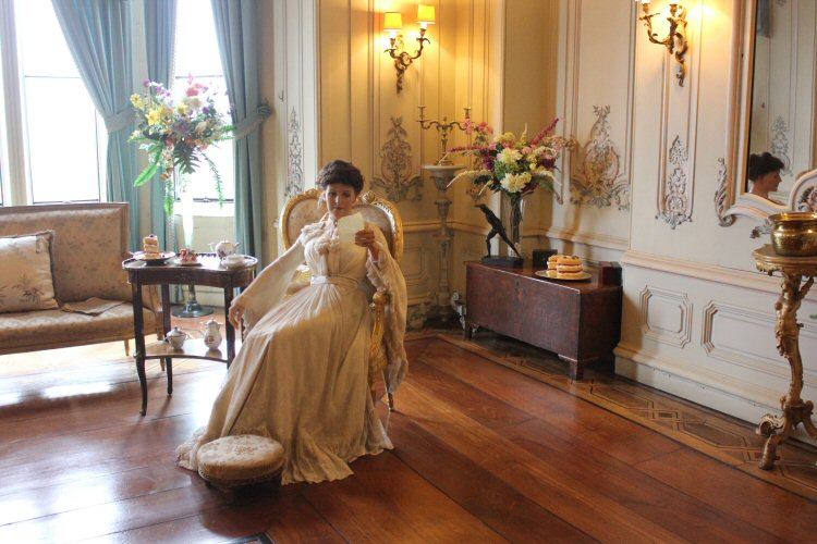 State of a seated Edwardian lady dressed as if for a house party - visiting Warwick castle with a toddler