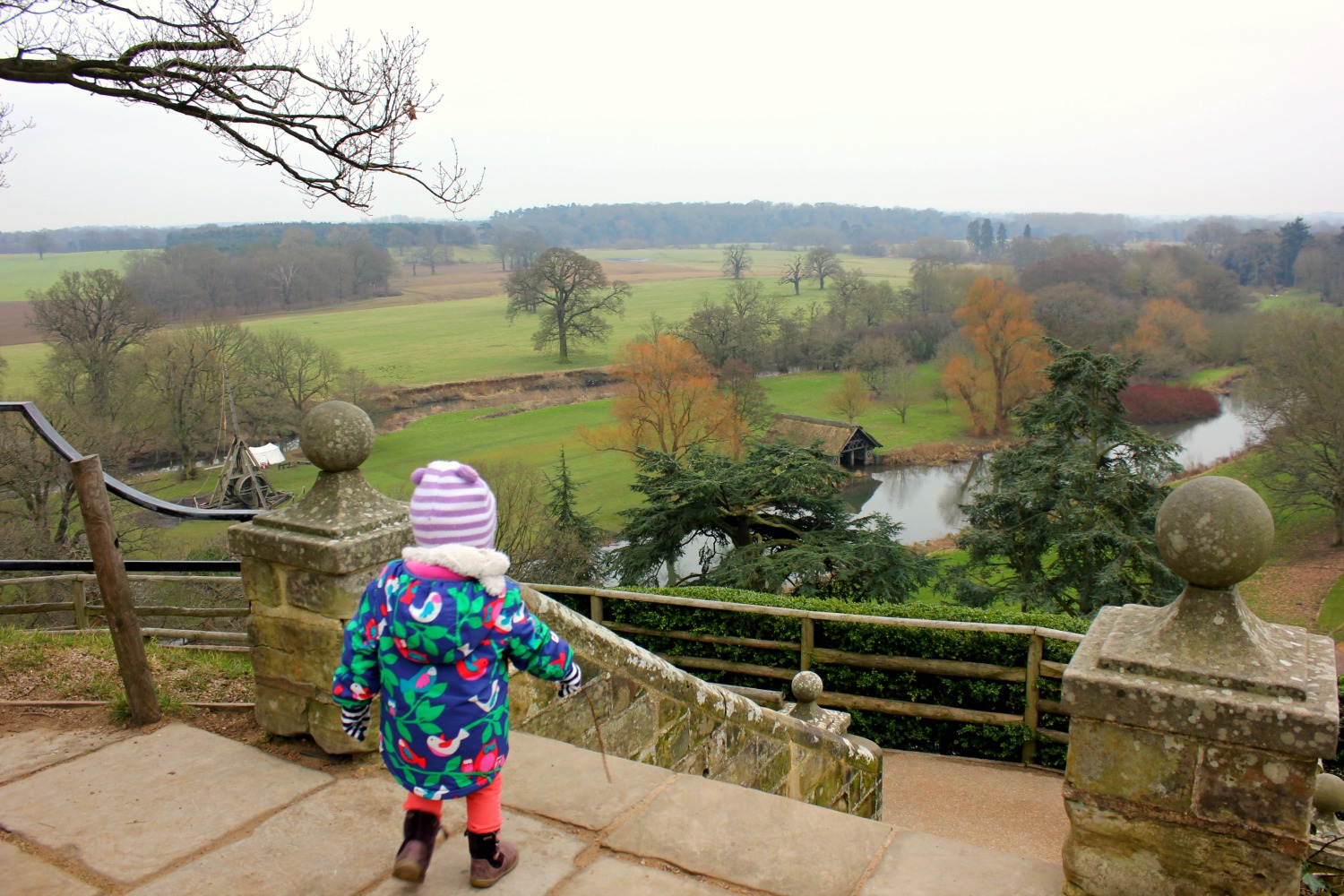 My daughter looks down the steps behind the castle onto the grounds - visiting Warwick castle with a toddler