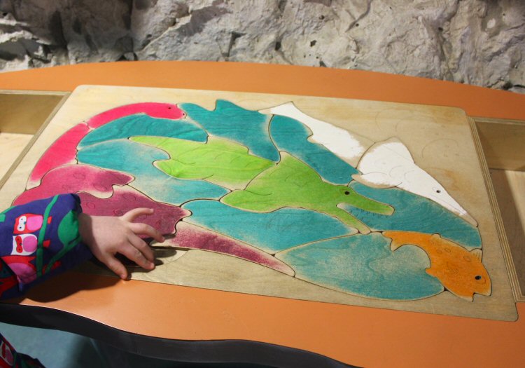 My daughter's hands as she tests out the dinosaur jigsaw at Dinosaur Isle