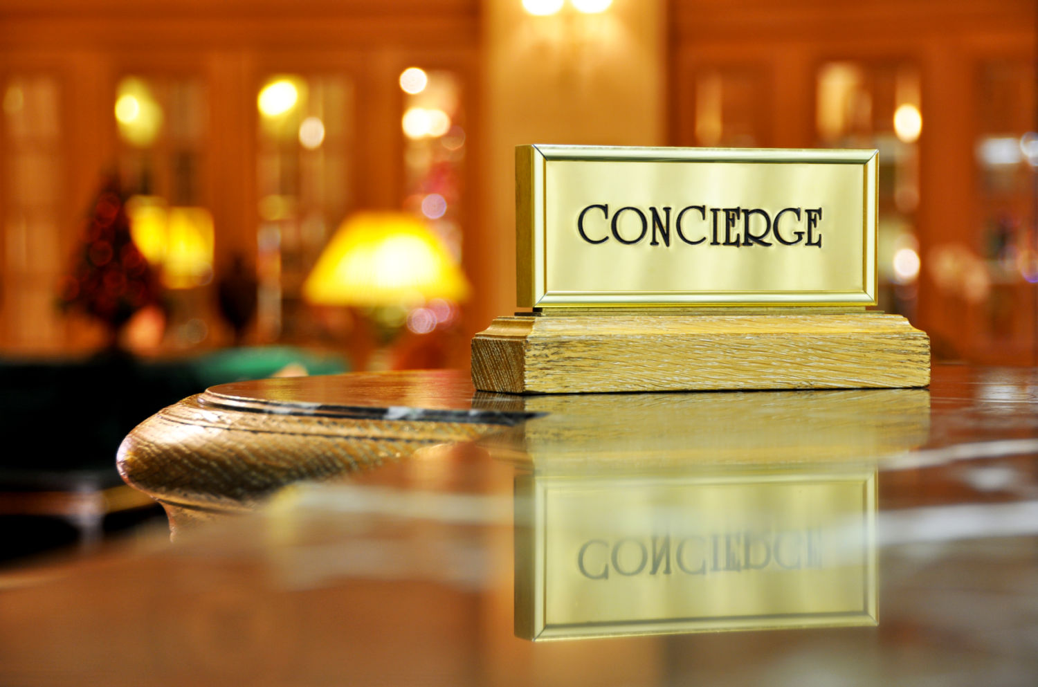 Golden sign on shiny table reading concierge with blurry hotel lobby in the background- my hotel employee wishlist