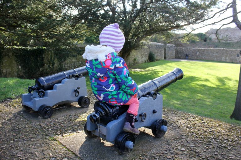 My toddler daughter sitting on a cannon at Carisbrooke Castle on the Isle of Wight