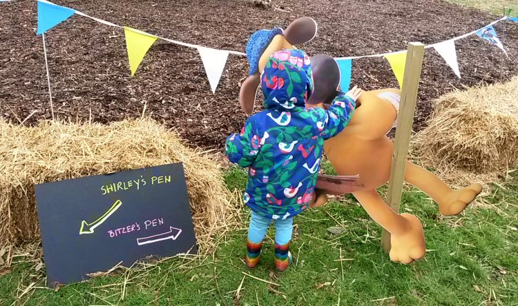 My daughter standing by a hay bale by the side of the sheep trials for Shaun the Sheep at Kew Gardens