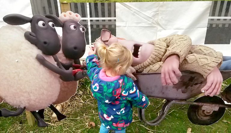 My toddler looks at one of the exhibits at the Shaun the Sheep event at Kew Gardens, with the farmer asleep in a wheelbarrow pushed by sheep