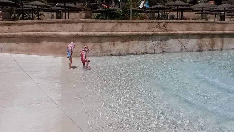 My two-year-old daughter tests the shallow water in tehw ave pool at Aqualand Gran Canaria - my review of a day at the water park in Maspalomas with kids