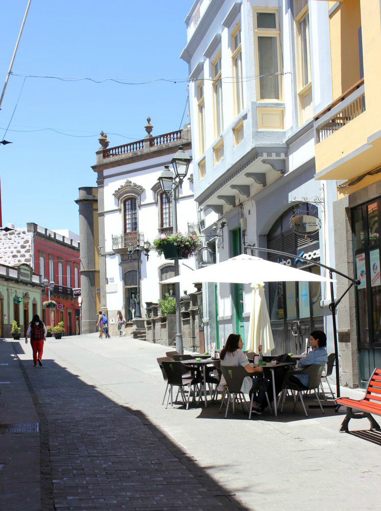 Cafe on a hilly street lined with pastel and white buildings in Arucas, Gran Canaria