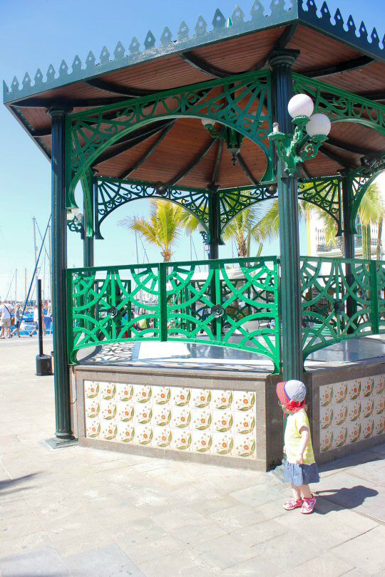 My daughter by the bandstand in Puerto de Mogan, Gran Canaria with palm trees in the distance