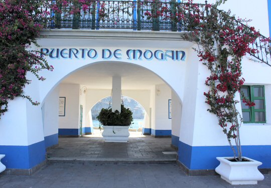 Blue painted sign saying Puerto de Mogan on a white building in Gran Canaria