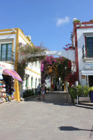 Pastel and white buildings around a flowery archway to a street in Puerto de Mogan, Gran Canaraia