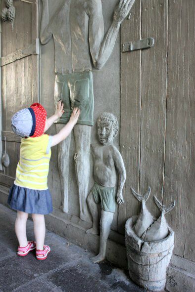 My toddler daughter touches one of the carved pictures of people on the street in Puerto de Mogan, Gran Canaria
