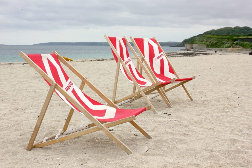 Red and white deckchairs on the sand of on Gyllyngvase beach in Falmouth, Cornwall
