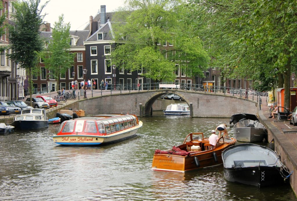 Boat cruising towards a bridge in Amsterdam - a canal cruise is included in the I Amsterdam pass. My review: is the I Amsterdam card worth it?