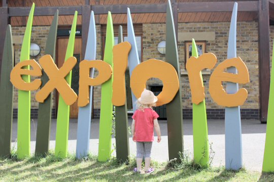 My daughter stands by the sign for the Explorer play area at the London Wetland Centre