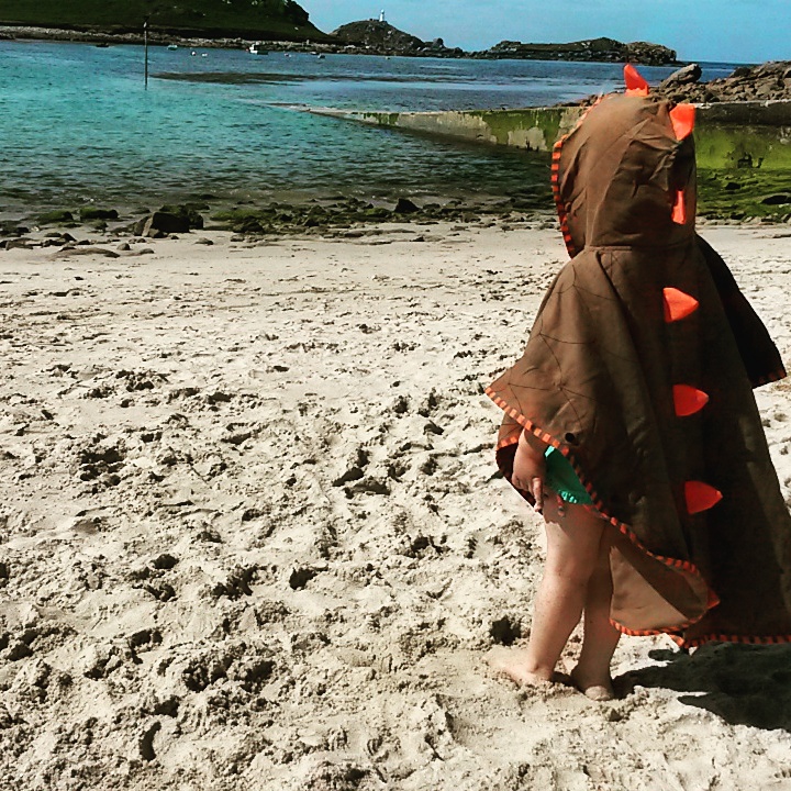 My daughter stands on the beach of St Martin's in the Isles of Scilly wearing a hooded dinosaur towel