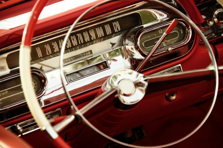 The steering wheel and red dashboard of a vintage car
