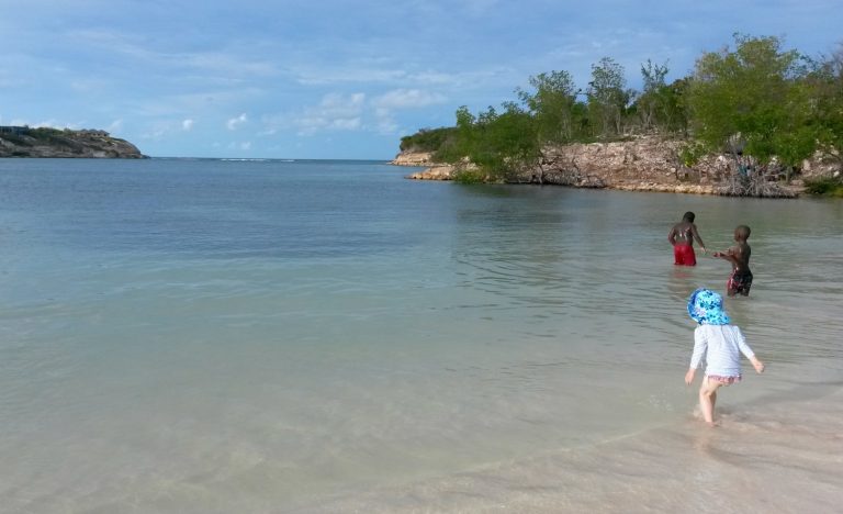 My daughter paddles in the sea at Verandah resort in Antigua - my Antigua travel lessons learned, from jetlag to swimming with stingrays