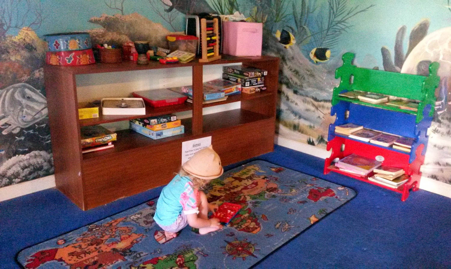 My daughter in swimming gear and hat plays on the carpet in the kids club at Verandah Resort in Antigua