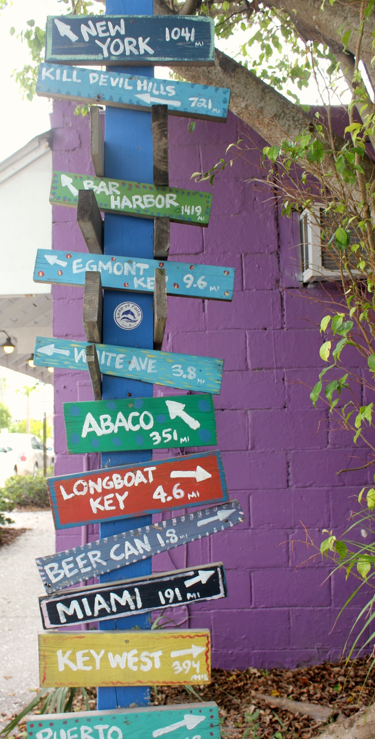 Sign post to various Florida destinations in bright colours against a purple wall