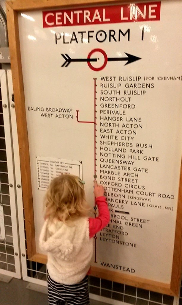 My daughter looks at an old tube line map - exploring the London Transport Museum depot with kids