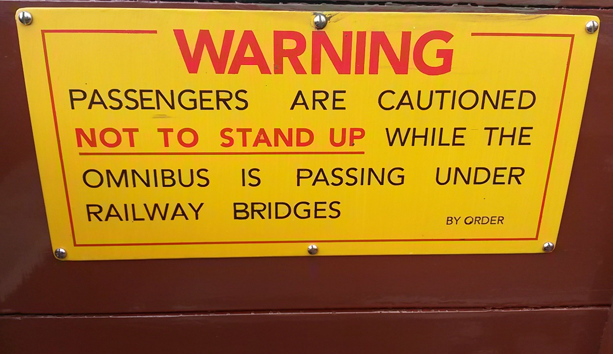 Sign warning passengers not to stand up while buses go under bridges - the London Transport Museum Acton depot open day