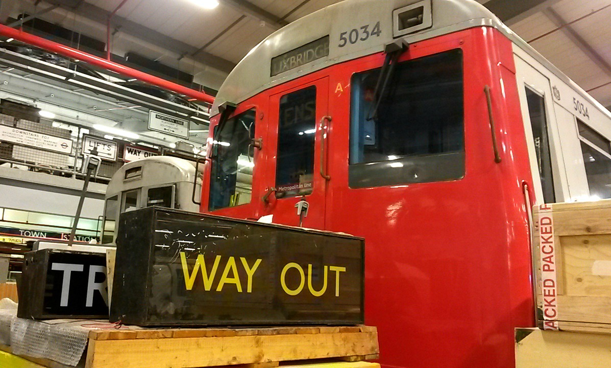 Old tube trains next to a way out sign - exploring the London Transport Museum depot with kids