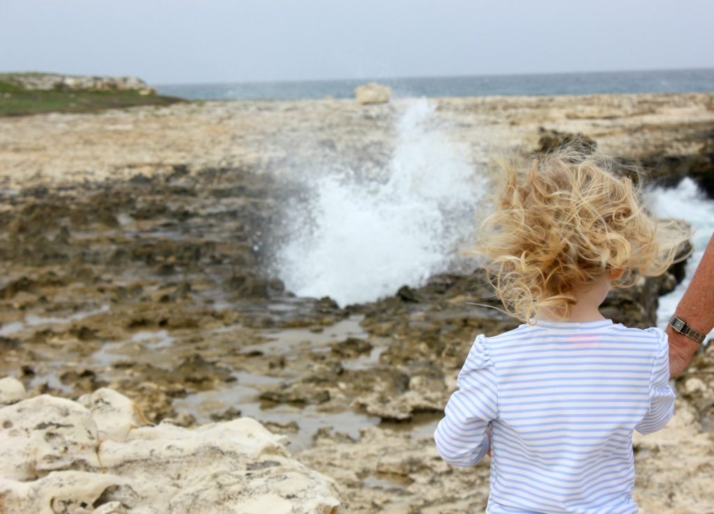 My daughter in her Sunuva rash vest watching the water crash at one of the blowholes at Devil's Bridge on Antigua - my Sunuva review both in and out of the pool