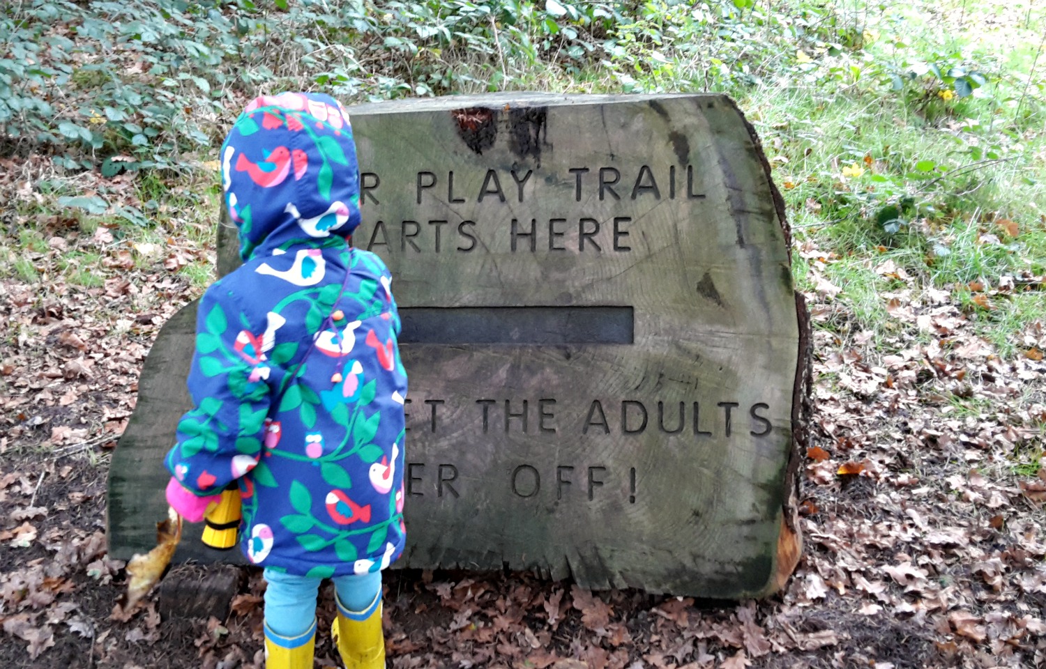 My daughter by the sign to the Osterley house playground - a natural play trail in the woods at the National Trust property
