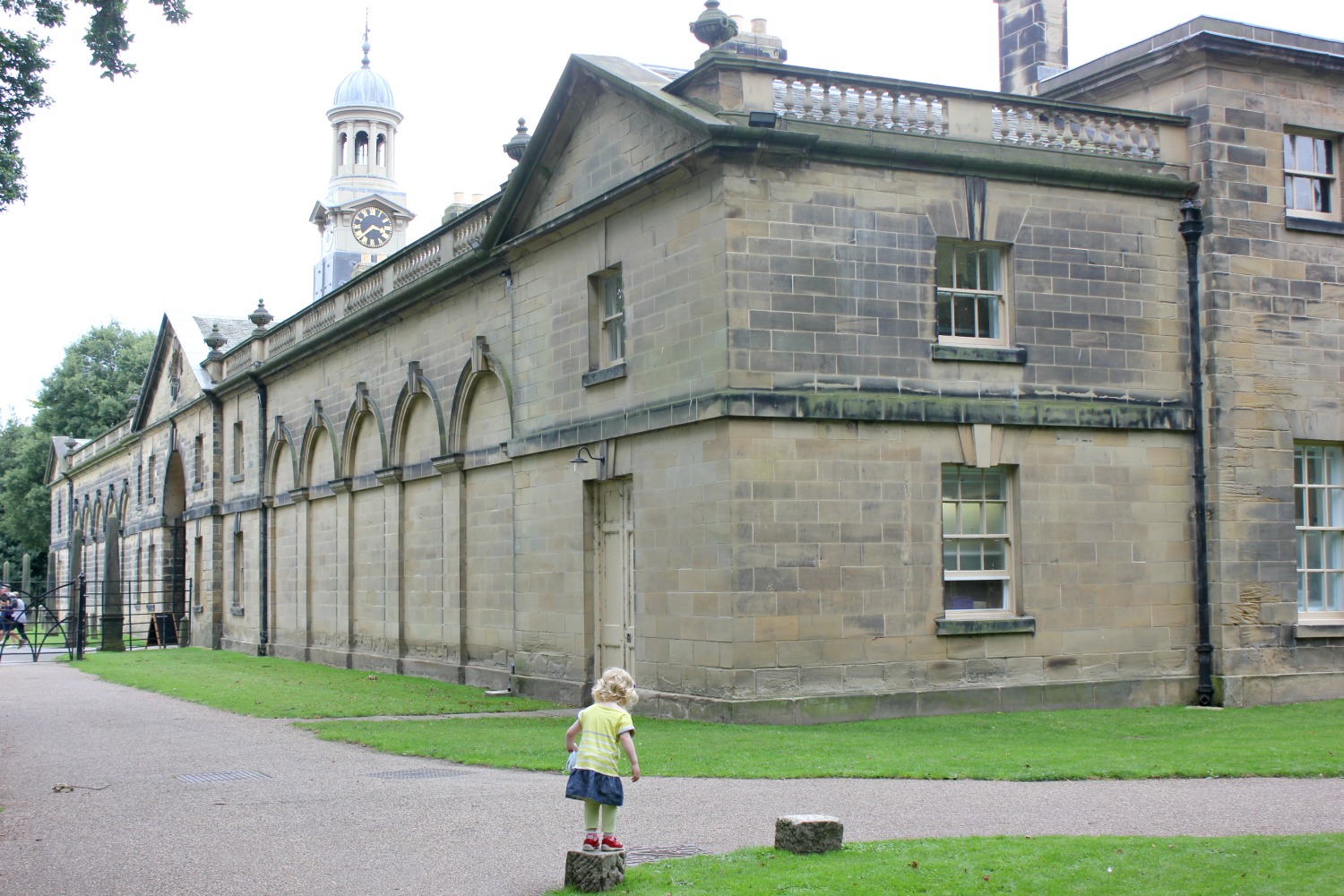 My daughter balancing on tree stumps with Nostell Priory in the background - visiting Yorkshire on a day out at Nostell Priory with kids