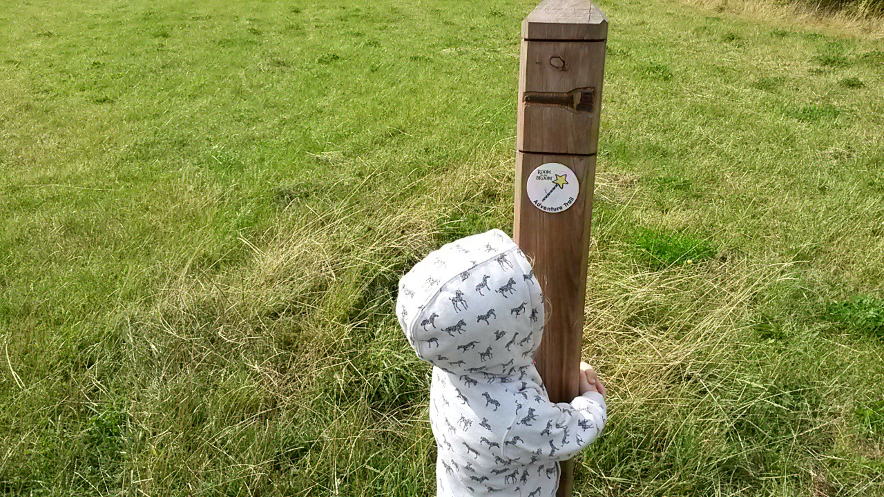 My daughter looks up at one of the trail posts with its wand symbol - my review of the Room on the Broom trail in Yorkshire